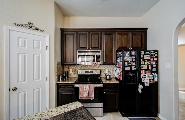 kitchen with light stone counters, backsplash, dark brown cabinets, and stainless steel appliances