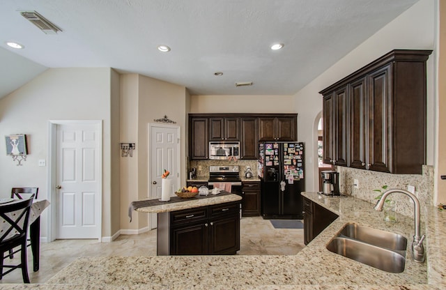 kitchen featuring appliances with stainless steel finishes, sink, backsplash, dark brown cabinetry, and kitchen peninsula