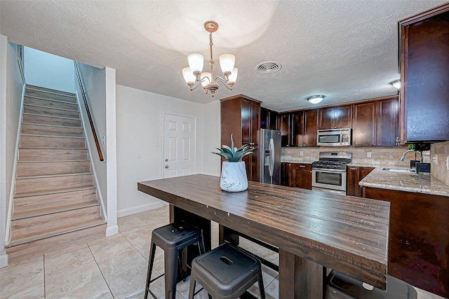 kitchen featuring decorative light fixtures, tasteful backsplash, sink, light stone counters, and stainless steel appliances