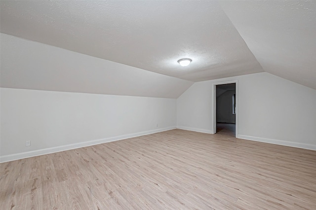 bonus room featuring vaulted ceiling, a textured ceiling, and light hardwood / wood-style flooring