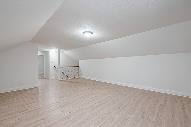 bonus room featuring vaulted ceiling, a textured ceiling, and light wood-type flooring