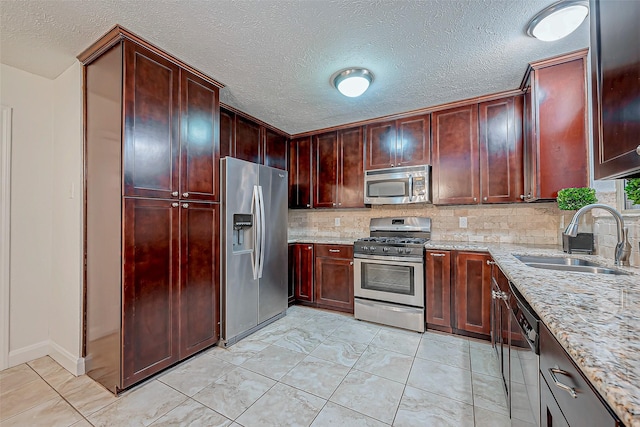 kitchen featuring sink, appliances with stainless steel finishes, light stone countertops, light tile patterned flooring, and decorative backsplash