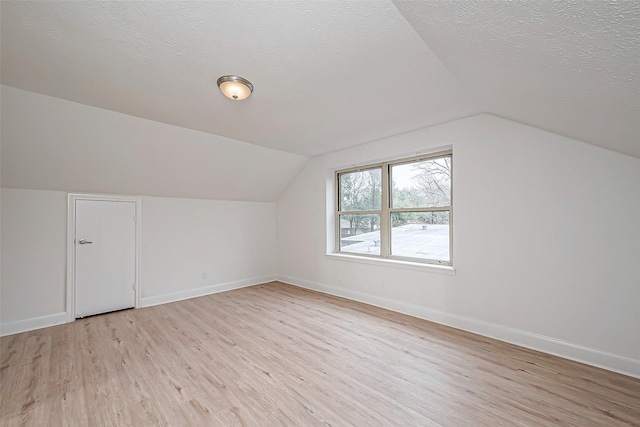 bonus room with vaulted ceiling, a textured ceiling, and light hardwood / wood-style floors