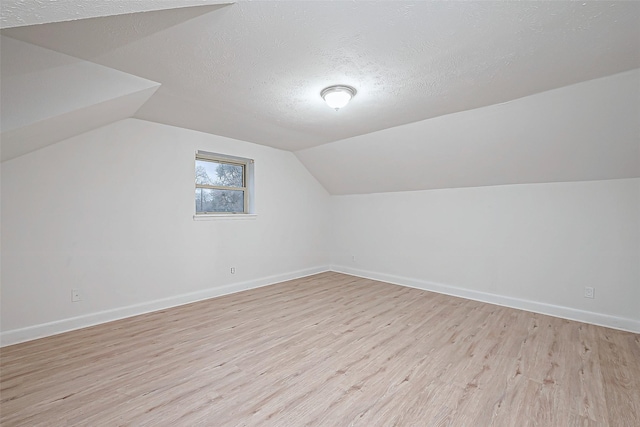 bonus room featuring lofted ceiling, light hardwood / wood-style floors, and a textured ceiling