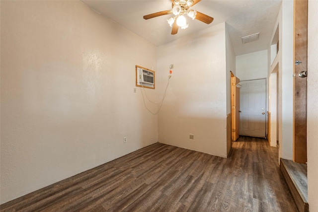 empty room featuring a ceiling fan, dark wood-style flooring, and a wall mounted AC