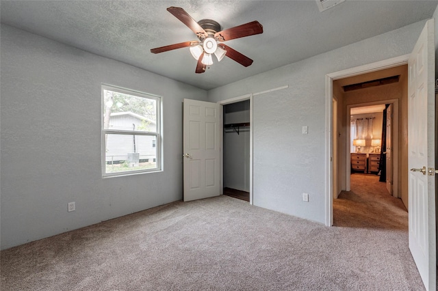 unfurnished bedroom featuring a ceiling fan, a textured ceiling, a closet, carpet flooring, and a textured wall