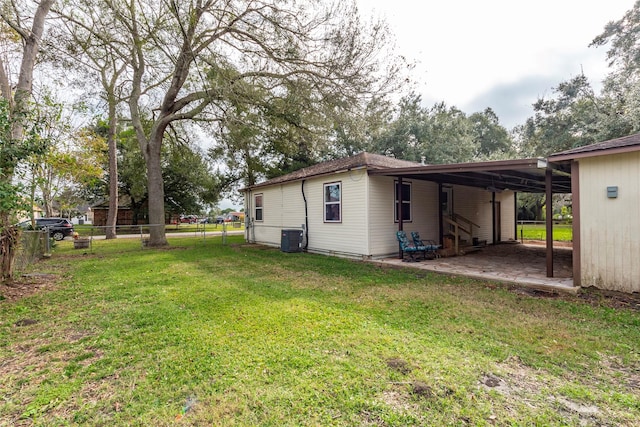 view of yard featuring a carport, central AC unit, and fence