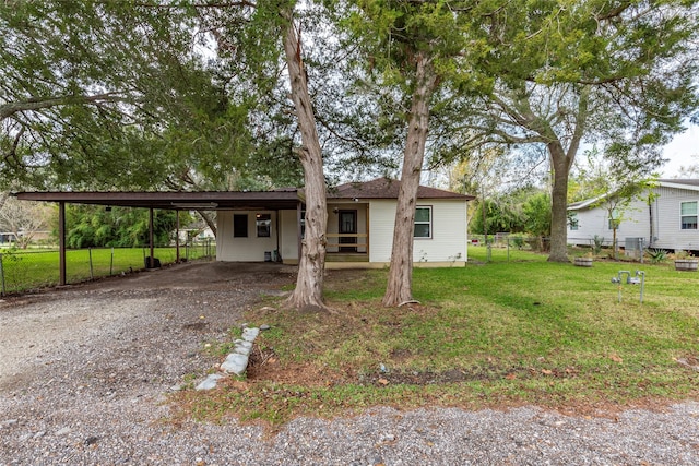 ranch-style home with an attached carport, fence, a front lawn, and driveway