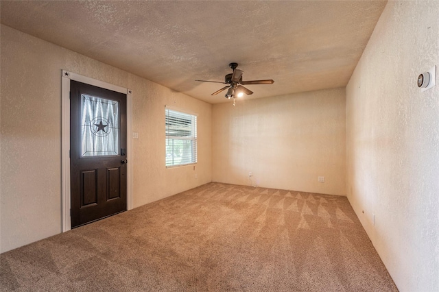 entrance foyer featuring a textured ceiling, a ceiling fan, carpet, and a textured wall