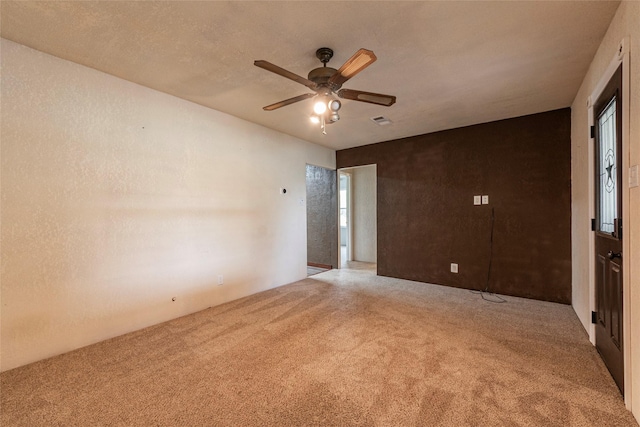 carpeted empty room featuring visible vents, a textured ceiling, and ceiling fan