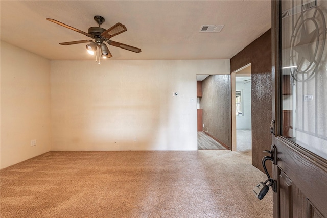 unfurnished room with visible vents, carpet floors, and ceiling fan