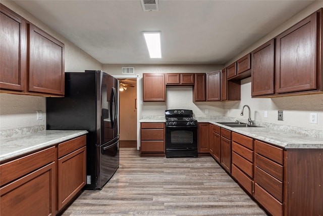 kitchen featuring light wood finished floors, visible vents, black appliances, and a sink