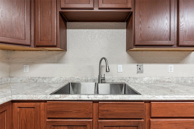 kitchen with light countertops, a textured wall, and a sink