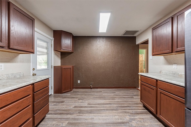 kitchen featuring light countertops, a textured wall, visible vents, and light wood finished floors