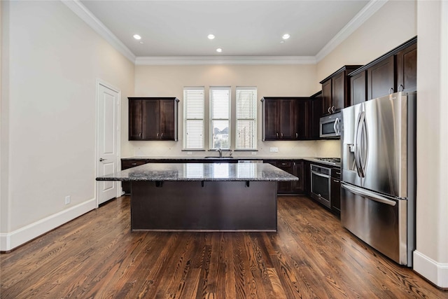 kitchen with a kitchen island, dark brown cabinetry, stainless steel appliances, and dark stone countertops