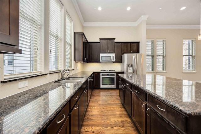 kitchen with dark wood-style flooring, appliances with stainless steel finishes, a sink, a center island, and dark stone counters