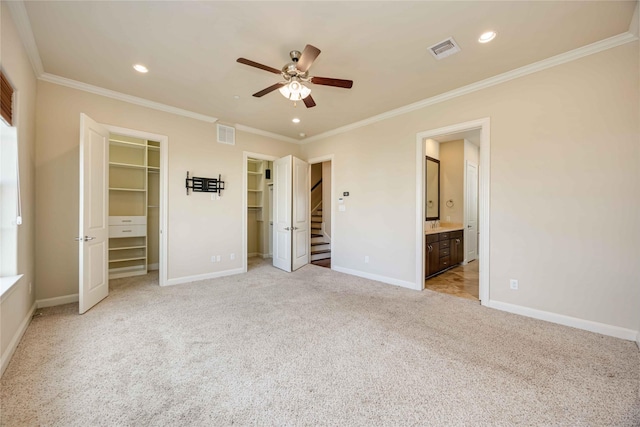 unfurnished bedroom with ceiling fan, light colored carpet, ornamental molding, and connected bathroom