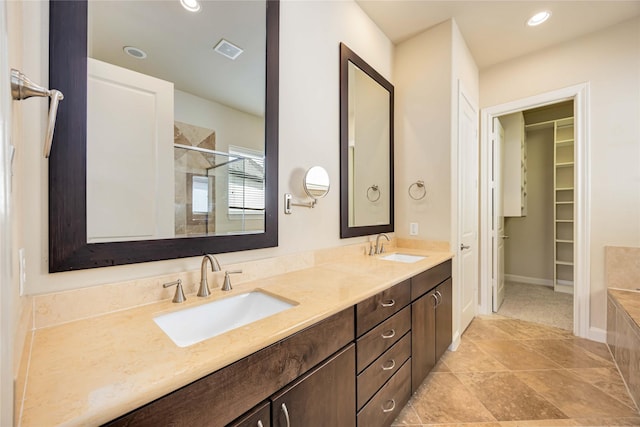 full bathroom with a sink, a shower stall, double vanity, and visible vents