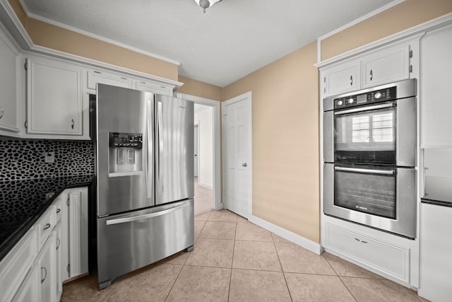 kitchen with light tile patterned floors, a textured ceiling, white cabinetry, appliances with stainless steel finishes, and dark countertops