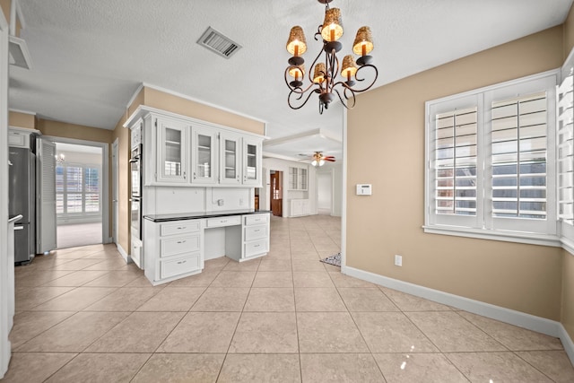 kitchen featuring built in desk, light tile patterned floors, stainless steel appliances, visible vents, and glass insert cabinets