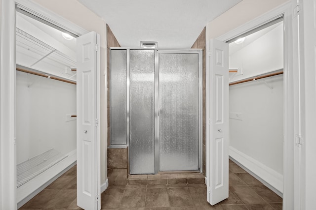 bathroom with a shower stall, a walk in closet, and tile patterned floors