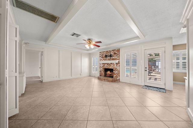 unfurnished living room featuring a brick fireplace, a raised ceiling, visible vents, and a decorative wall