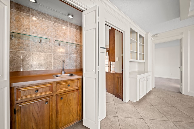 interior space featuring light tile patterned floors, a textured ceiling, indoor wet bar, and a sink