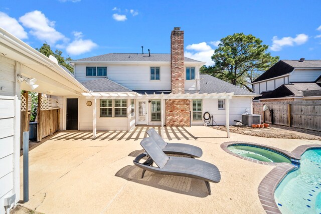 back of house with a patio, a chimney, central air condition unit, an in ground hot tub, and a fenced backyard