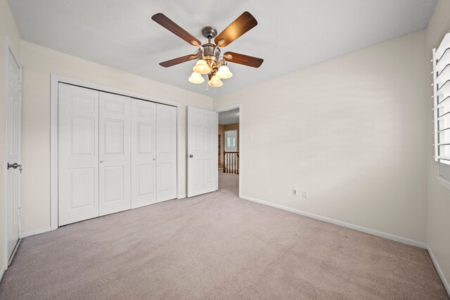 unfurnished bedroom featuring carpet, a closet, ceiling fan, and baseboards