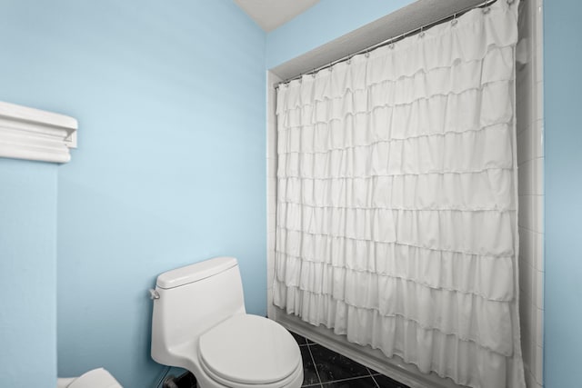 bathroom featuring tile patterned flooring, shower / tub combo, and toilet