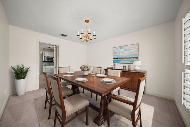 dining room featuring baseboards, visible vents, a chandelier, and light colored carpet