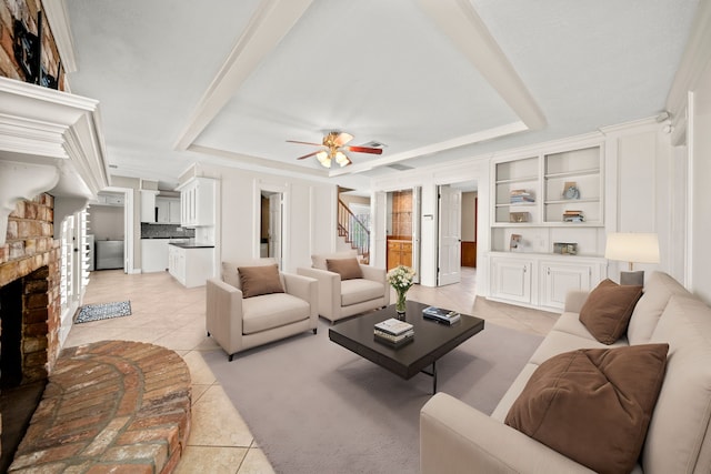 living room featuring a brick fireplace, light tile patterned floors, and a tray ceiling