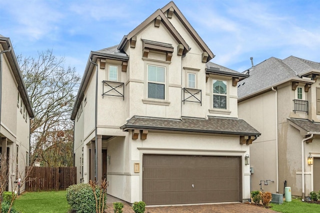 view of front of property with a shingled roof, decorative driveway, fence, and stucco siding