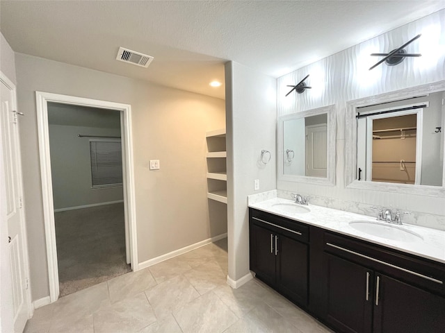 full bathroom featuring a spacious closet, visible vents, double vanity, and a sink