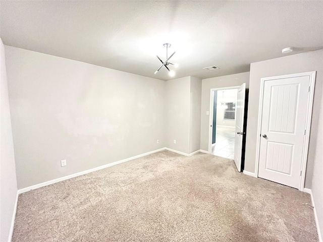 empty room featuring light carpet and an inviting chandelier