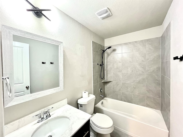 full bathroom featuring toilet, tiled shower / bath combo, vanity, and a textured ceiling