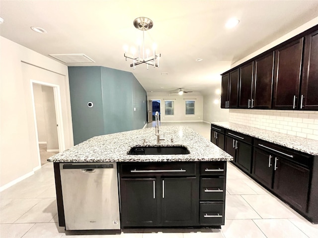 kitchen featuring a kitchen island with sink, a sink, dishwasher, ceiling fan with notable chandelier, and tasteful backsplash