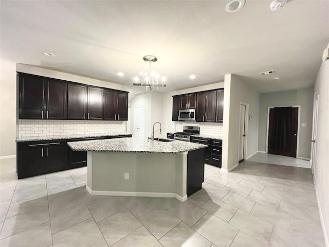 kitchen featuring a chandelier, light stone countertops, appliances with stainless steel finishes, and a sink