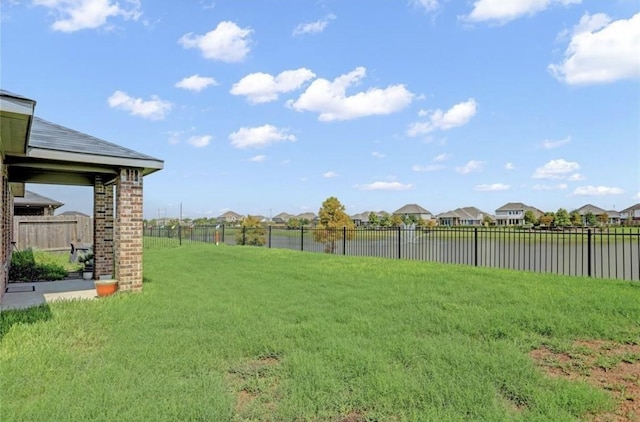 view of yard featuring fence, a residential view, and a water view