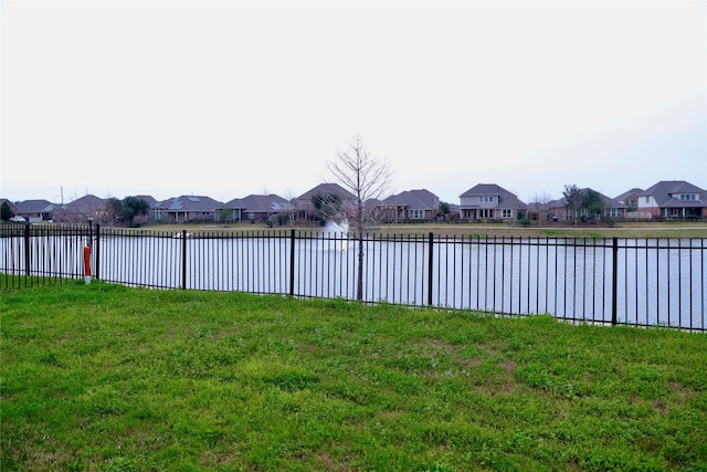 view of yard with a residential view, fence, and a water view