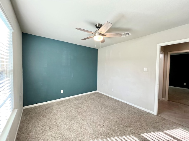 empty room with visible vents, baseboards, ceiling fan, and carpet floors