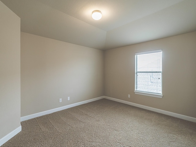 carpeted empty room featuring vaulted ceiling