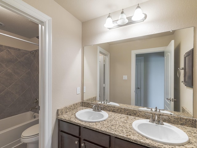 full bathroom featuring vanity, tiled shower / bath, and toilet