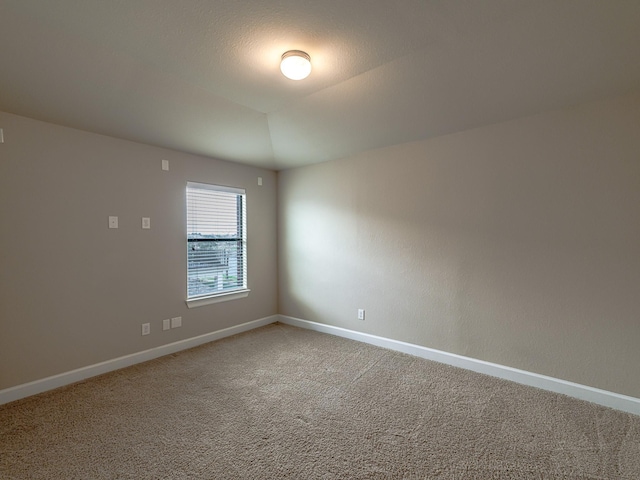 carpeted spare room with vaulted ceiling