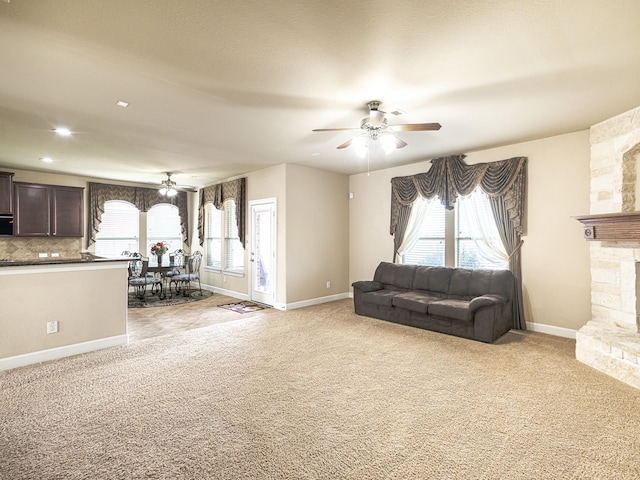 living room featuring light carpet, a fireplace, and ceiling fan