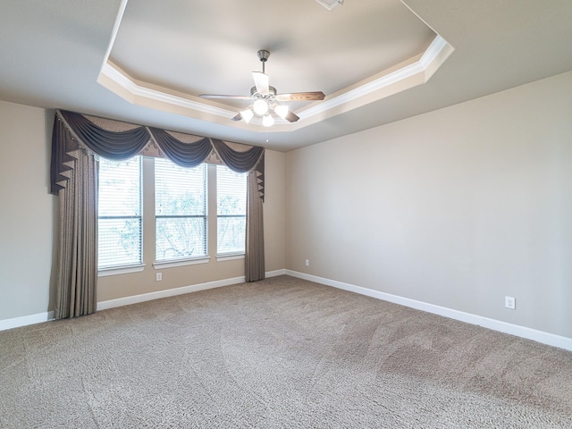 unfurnished room with a raised ceiling, ornamental molding, carpet floors, and ceiling fan