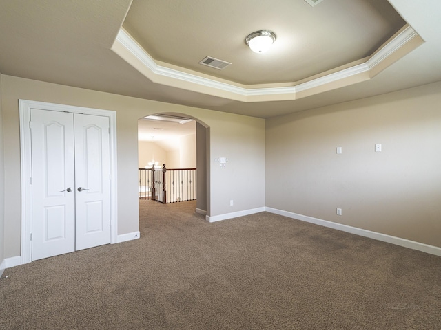 unfurnished bedroom with crown molding, a raised ceiling, and carpet