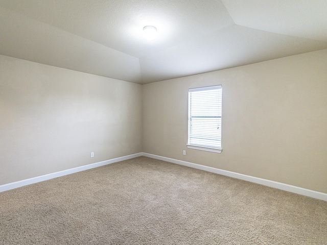 carpeted spare room featuring lofted ceiling