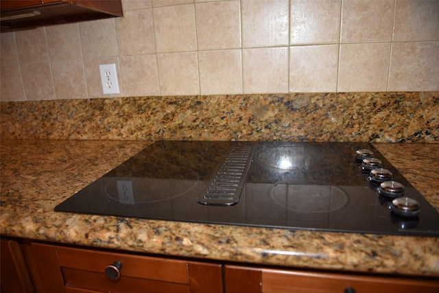 room details featuring decorative backsplash, black electric cooktop, and dark stone counters