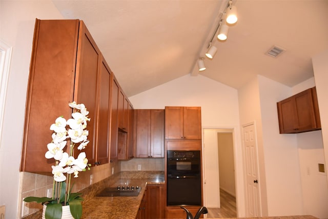 kitchen with dark stone countertops, lofted ceiling, decorative backsplash, and black appliances